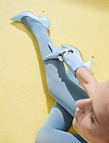 Model wearing blue pumps with blue stockings against yellow floor.